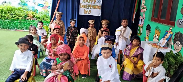 A group of children in freedom-fighter fancy dress under a Happy Independence Day banner
