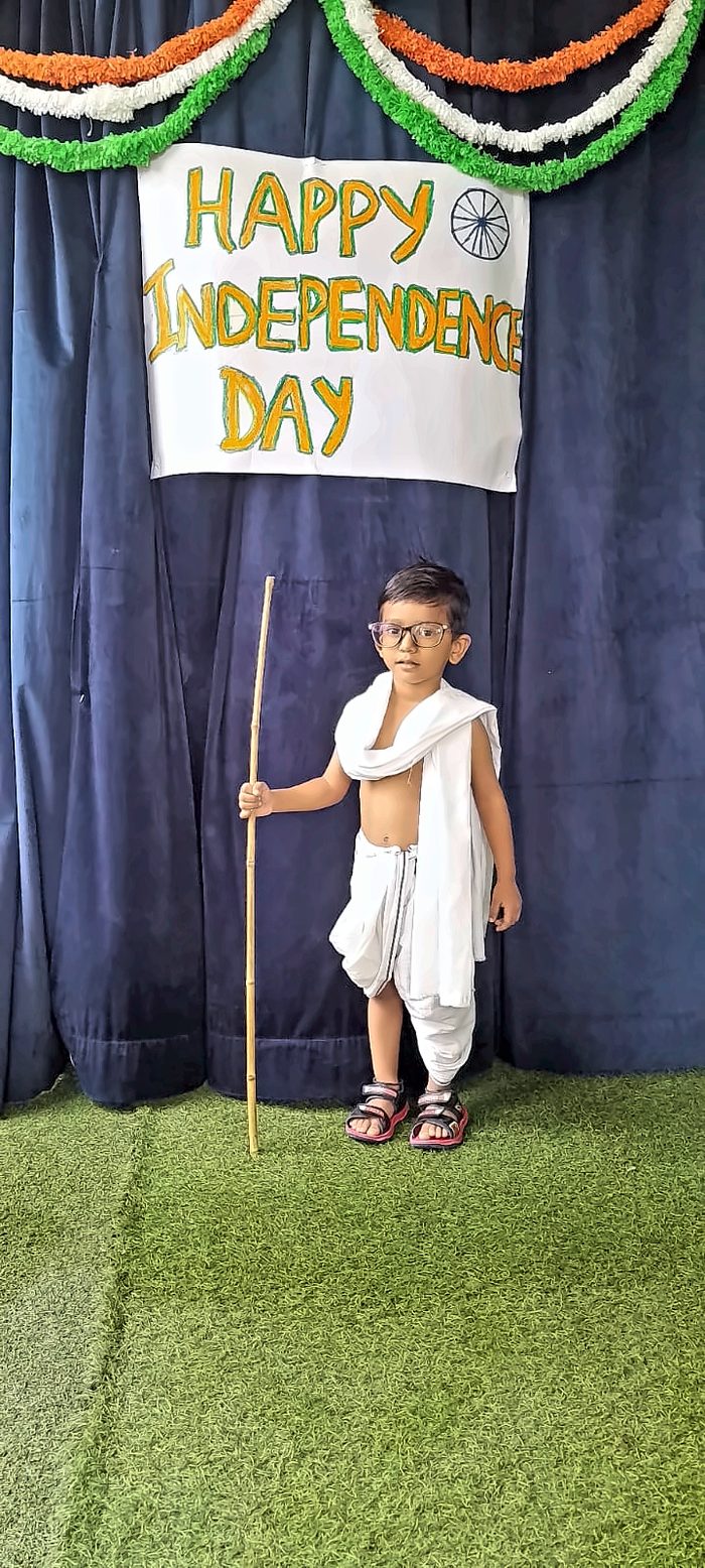 A child dressed as Mahatma Gandhi holding a bamboo staff