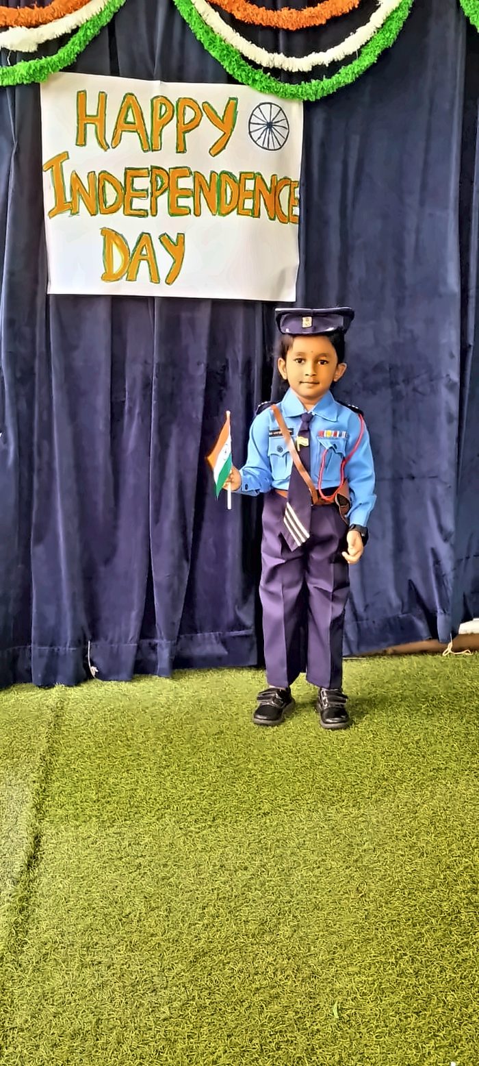 A child in an air-force style uniform holding a small Indian flag