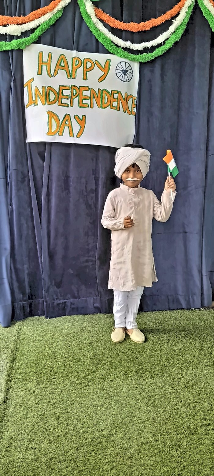 A child in a turban and kurta waving a paper Indian flag