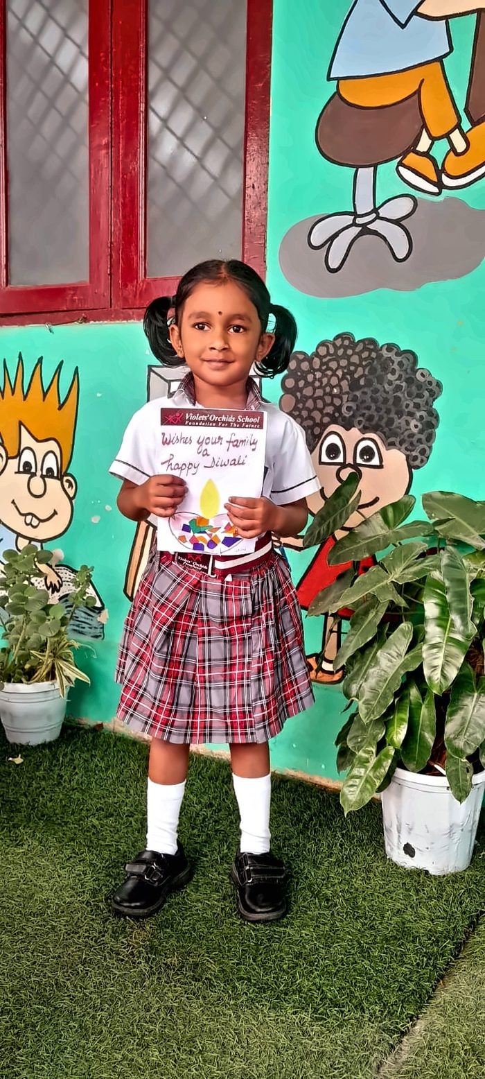 A girl in school uniform holding her handmade Diwali card