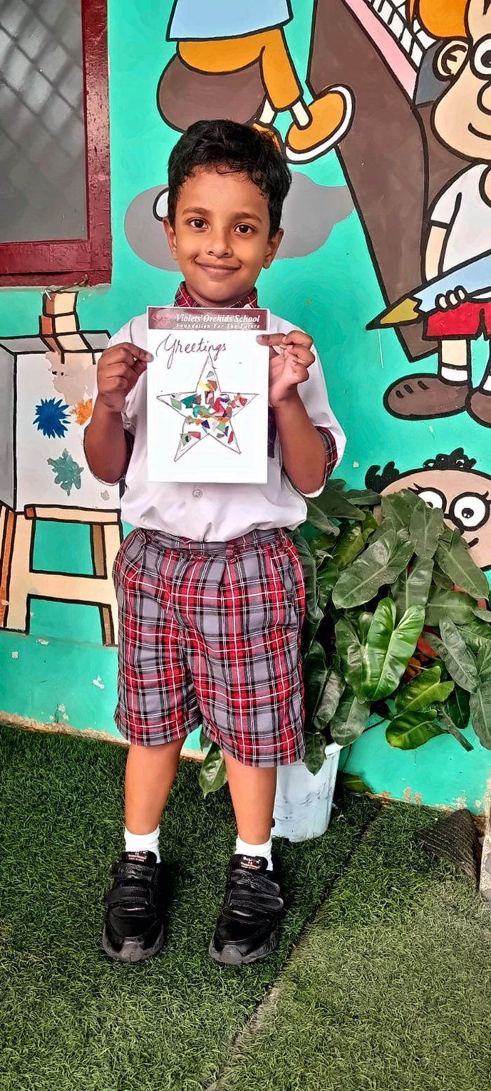 A boy holding up his mosaic star greetings card