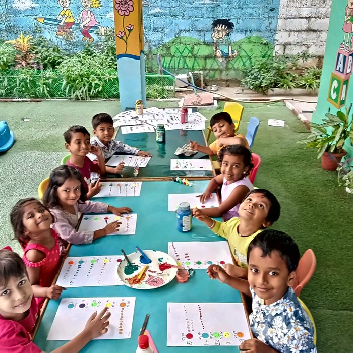 Children smiling around a long table during a fingerpaint counting activity
